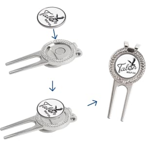 A silver golfers divot tool with a detachable ball marker, featuring a logo and intricate detailing.