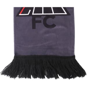 A grey velvet scarf featuring a logo and black fringes at the ends, designed as a clothing accessory.