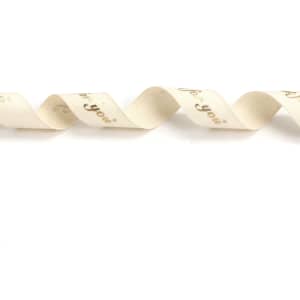 A wavy, cream cotton ribbon with hot stamping in gold. It features a decorative design and includes a logo.