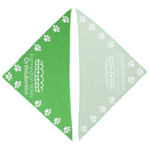 A green and light green triangular pet bandana with a paw print pattern. It features a logo on one side.