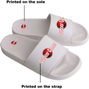 White PVC slides with printed designs on the strap and sole, featuring branding elements.