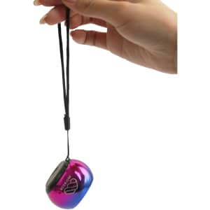 A mini bass wireless speaker in a gradient of pink and blue, held by a hand with a wrist strap attached.