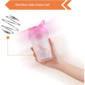 A drink bottle with a pink lid and a clear body, featuring a stainless steel shaker ball inside and a loop.