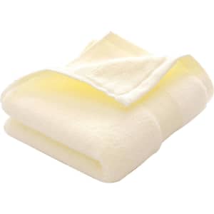 A folded embroidered cotton hand towel in soft yellow, featuring a subtle texture and a logo.
