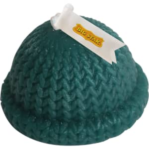 A teal hat-shaped candle with a textured knit design and a ribbon detail, featuring a small logo on it.