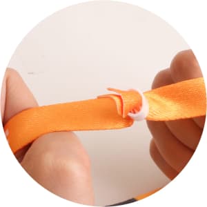 An orange RPET fabric wristband being secured with a plastic connector, held in hands.
