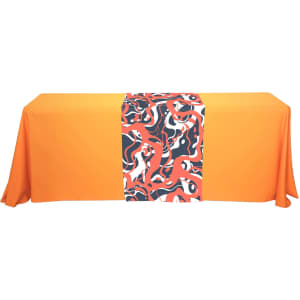 A small table runner featuring a vibrant abstract pattern, placed on an orange tablecloth.