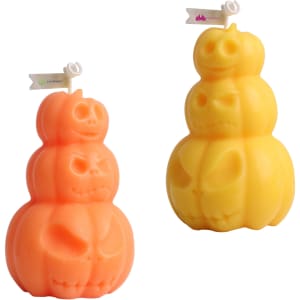 Triple pumpkin-shaped candles in orange and yellow, featuring carved pumpkin faces. Includes branding on a small flag.