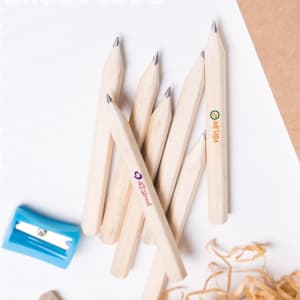 A collection of six short grey-lead pencils and a blue pencil sharpener on a white surface.
