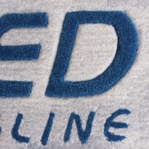 Acrylic fibre logo mat in grey and blue, featuring a prominent logo design.