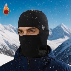 A black balaclava face mask worn by a person in a snowy mountain landscape with a logo visible.