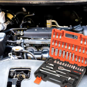 A mechanic socket set in an orange and black case, laid out near a vehicle engine.
