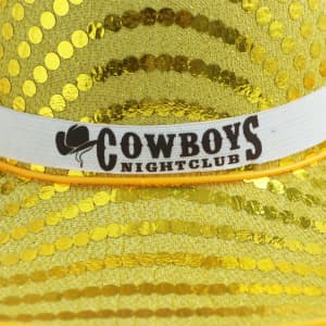 A shiny yellow sequin cowboy hat with a white band featuring a logo.