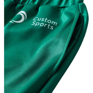 A close-up of unisex adult sports shorts in green, featuring a logo and a smooth polyester fabric.