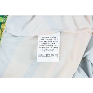 A care label on a 100% polyester micro mesh sports long sleeves shirt, featuring fabric care instructions.