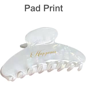 A transparent acetate hair clip in white with a glossy finish and an elegant design. Features a logo on the side.