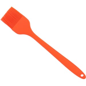 An orange silicone pastry brush with a long handle and grooved bristles. It features a hanging hole for storage.