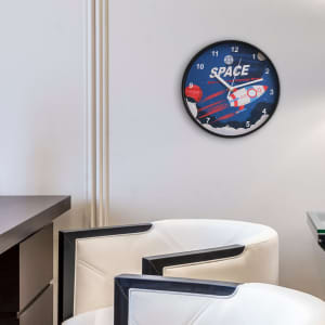 A round wall clock featuring a space theme with a rocket, in blue, white, and red colours. It has a logo.