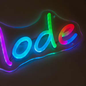 A neon LED sign featuring colourful, glowing text in various shades, displayed against a dark background.