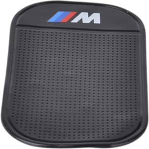 A black dashboard mat with a textured surface and a branded logo on one side.