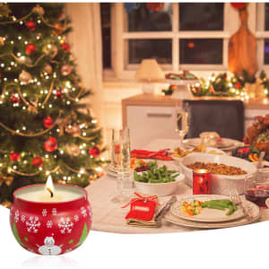 A red tin candle with a snowman design, placed near a festive dinner setting and Christmas tree.