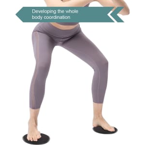 A pair of black yoga sliding disks on a white background, with a person performing a stance wearing grey leggings.