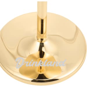 A stainless steel martini goblet with a shiny gold finish and a base that has a logo.