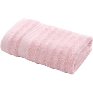 A folded bamboo fibre towel in soft pink, featuring a textured design and a subtle strap.