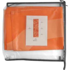 An orange medium table runner packed in a clear bag with a grey zipper. It includes a product information card.