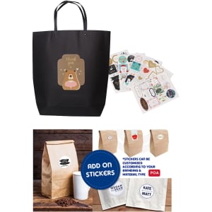 A large black paper boutique bag with handles and various stickers displayed beside it.