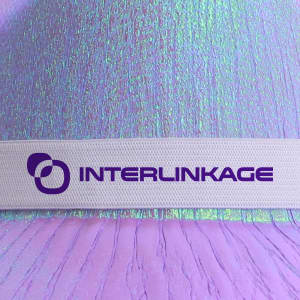 Iridescent cowboy hat in shades of purple and pink, featuring a white band with a logo.