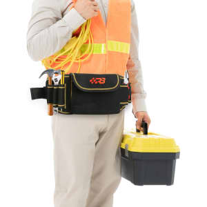 A waist tool bag in black with red accents, worn by a person holding a yellow tool box and wearing a high-visibility vest.