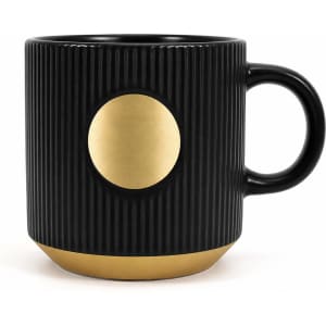 A ceramic coffee mug in black with a bronze medal accent and ribbed texture. Features a handle and a logo.