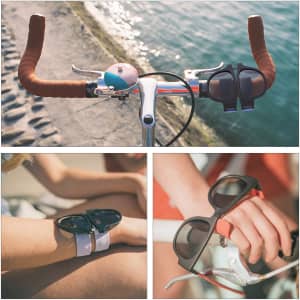 Slap band sunglasses in black, displayed on a bike handlebar and worn on a wrist, near water.
