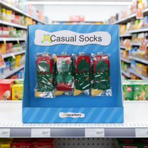 A display stand featuring festive socks in red, green, and yellow, set against a colourful store aisle backdrop.