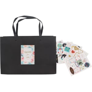 A black paper bag with a knitted handle and a decorative label, accompanied by assorted stickers.