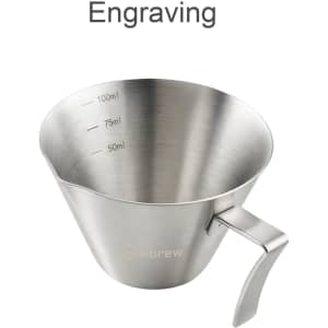 A stainless steel espresso measuring cup with measurements marked inside, featuring a handle and a logo.