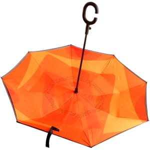An orange reversible folding umbrella with a curved handle and a contrasting inner layer design.