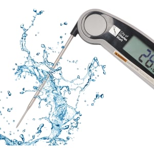 A digital instant read meat thermometer with a silver body and stainless steel probe, surrounded by splashes of water.