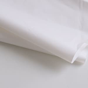A white biodegradable mailer bag with a smooth texture, slightly crumpled and folded on a light surface.