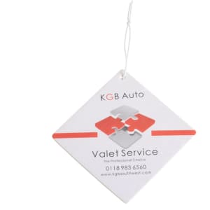 A square air freshener in white with red and grey puzzle design, featuring a hanging string and a logo.