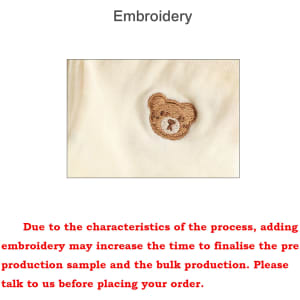 A close-up of a cream coloured fabric featuring a brown teddy bear embroidery.