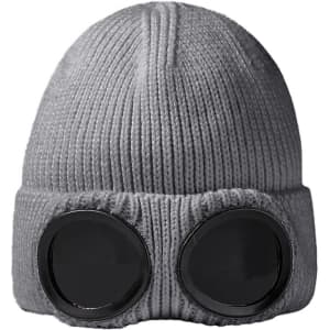 A grey beanie featuring large black goggles on the front, with a textured knit design. It includes a logo.