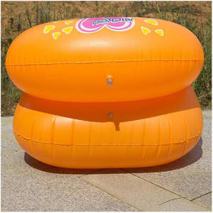 Two orange custom inflatable chairs stacked on a paved surface, featuring a logo on the front.