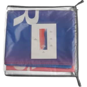 A large table runner in shades of blue and red, stored in a transparent zippered bag with a card insert inside.