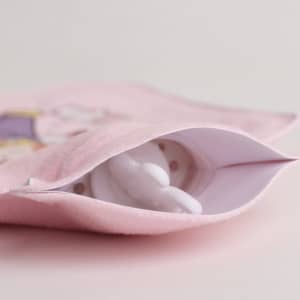A hot water bottle in white, nestled inside a pink plush cover featuring a cute design.