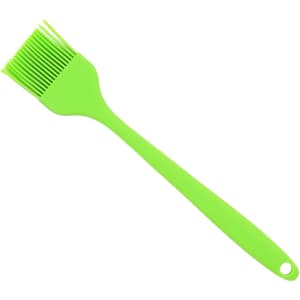 A green pastry brush with a flexible silicone head and a long handle, featuring a hole for hanging.