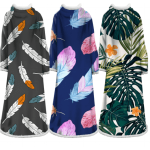 A blanket featuring three designs: feather patterns in grey, vibrant leaves on navy, and tropical leaves with flowers on white.