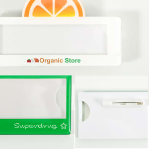 A custom reusable acrylic name badge in white and green, featuring a logo and a pin attachment.