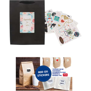 A medium vertical black paper bag with a fabric flat handle, alongside assorted colourful stickers and a kraft bag.